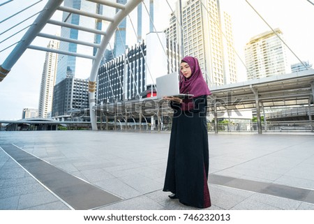 Muslim asian business woman working with laptop in public, against modern building