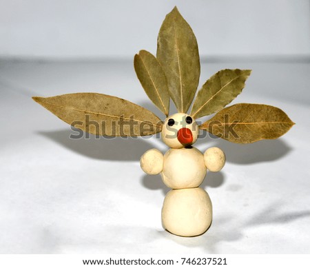 A figurine of a snowman made of plasticine. Autumn leaves on the head