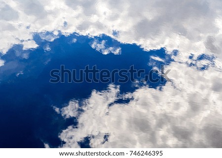 reflections of tranquil blue sky with white clouds on water III