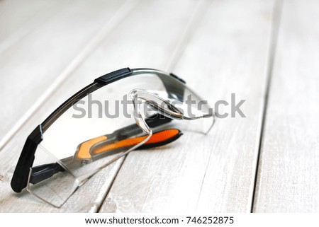 Black Plastic Protective Work Glasses on a White wooden table Background.