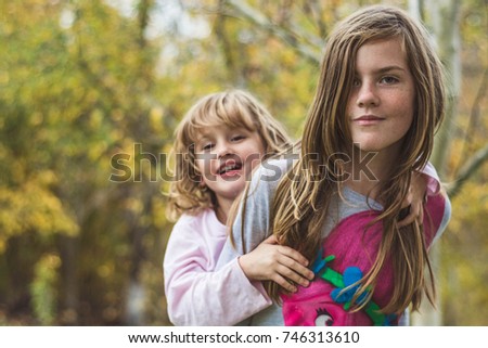 Young sisters hugging happy in their backyard.