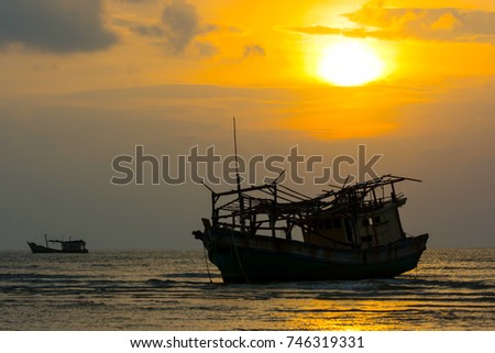 SILHOUETTE FISHERMAN BOAT WRECK AGROUND ON LOW TIDE AT SEASIDE , WONDERFUL SHINING SUN TWILIGHT SKY CLOUD IN BACKGROUND