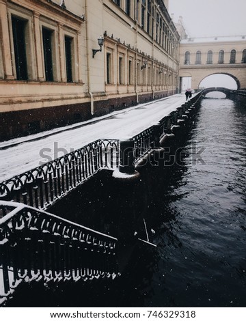 Narrow river near ancient buildings. Beautiful landscapes. Snowfall in calm city. Wonderful nature. Outdoor picture. Nice great scenery. Early January morning in town