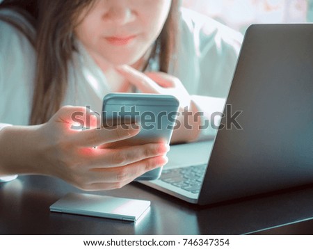 beauty hand from asian business woman(30s to 40s) with white shirt hold her smart phone and use computer laptop for support her business with soft focus background(girl smile)