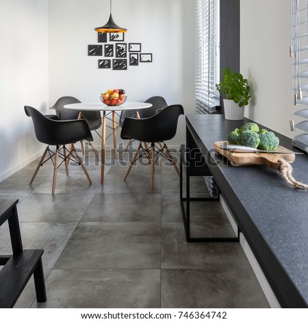 Kitchen with long, granite countertop, concrete floor tiles and round table and chairs