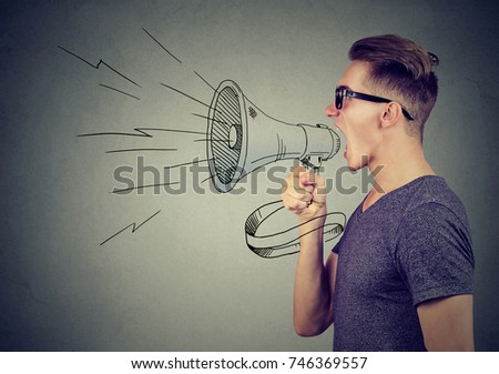 Young man screaming in a megaphone making announcement   Royalty-Free Stock Photo #746369557