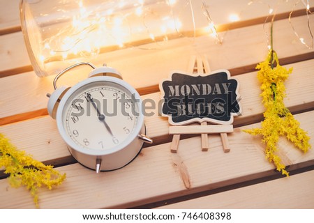 Conceptual image of Monday Blues word on a chalkboard with clock over nice light and wooden background