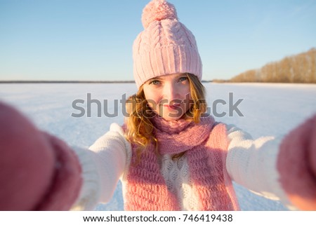 Pretty young female tourist takes selfie in winter field.
