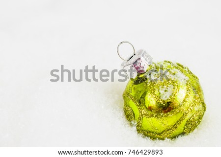 Close-up of green xmas ball under snowflakes in snow. Christmas and New Year concept with copy space. Christmas greeting card.