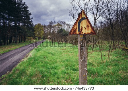 Rusty turn sign next to country road in Kampinos Forest near Warsaw, Poland