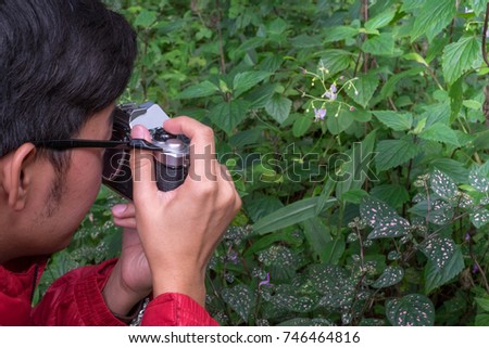 Asia young Scientists explore forests in Asia. hand holding camera. discovery concept,
Wildlife conservationist, Wildlife Photographer holding pro digital mirrorless camera with macro lens