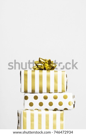 Group of gifts in white and gold paper on a gray background