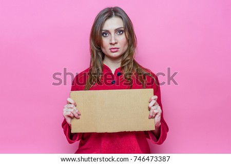 portrait serious cute young brunette girl with long haire in red pajamas with a cardboard sign in hands. Template.
