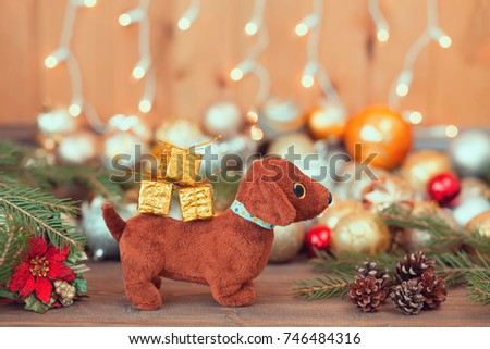 Year of the dog. Dog with a gift on a wooden background. Christmas balls, pine cones, a composition of the new year in golden color. The year of the dog on a horoscope symbol. Toned photo