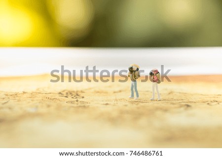 Travelling concepts. Two traveler miniature mini figures with backpack standing on map.
