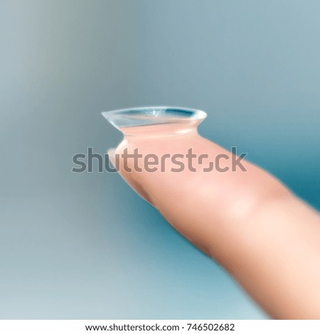 girl holds finger on a contact lens, closeup