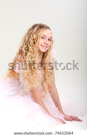 beautiful little girl in  dress with long hair on grey background