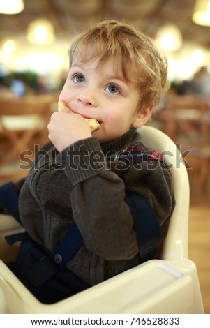 Kid eating pizza in highchair in cafe