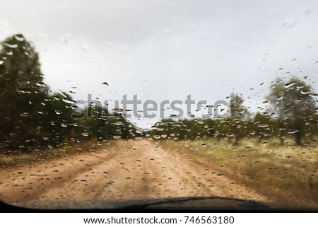 Raindrops on the windshield on the blurred background of a country road