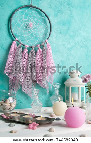 Pink gray lace dream catcher close up and pink and cream candles  on aquamarine textured background. Copy space for text.