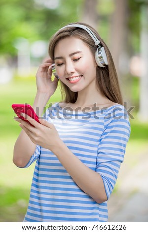 woman smile happily and use phone listen music in the park
