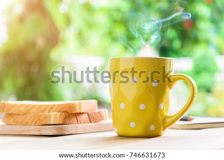 Good morning black coffee cup and bread on a wooden table in the sunrise background. breakfast and wake up