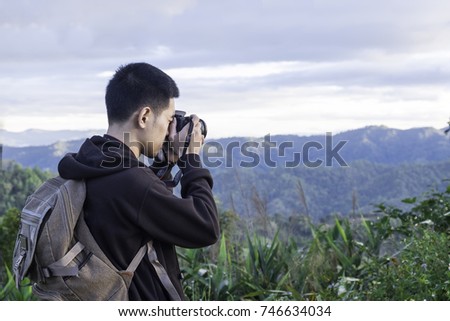 Nature photographer tourist with camera shoots while standing on top of the mountain
