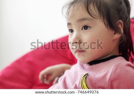 Happy little girl looking at cartoon on the couch