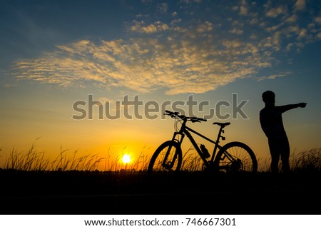 Lover cyclist and Bicycle silhouettes on the dark background of sunsets