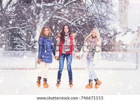Beautiful skating girls. Open air rink at winter. Falling snow. Christmas concept. 