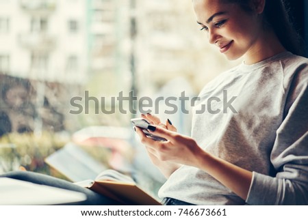 Cropped image of happy hipster girl having funny online chatting with friends in social networks on smartphone connected to wifi.Positive young woman enjoying leisure time in coffee shop with gadget