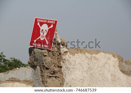 White skull-and-crossbones symbol on a red sign warning of the danger of landmines, Democratic Republic of Congo Royalty-Free Stock Photo #746687539
