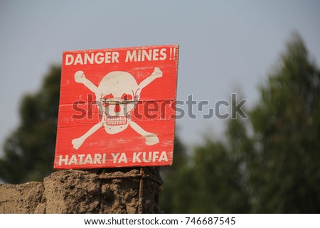 White skull-and-crossbones symbol on a red sign warning of the danger of landmines, Democratic Republic of Congo Royalty-Free Stock Photo #746687545