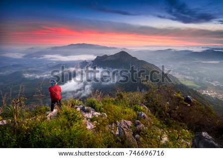 Hiker staring at the gorgeous view of the Pulai Mountain Kedah, Malaysia during sunrise. Noise image and soft focus due to long exposure high ISO.