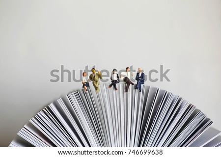 Miniature people: Businessman reading newspaper and sitting on book using as background education or business concept. Royalty-Free Stock Photo #746699638