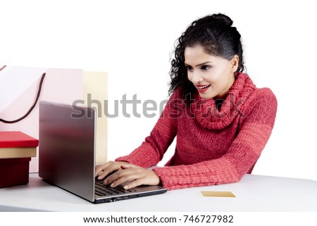 Picture of Indian woman wearing winter clothes while shopping online with a computer laptop, isolated on white background