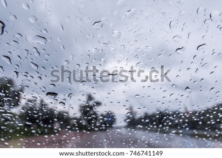 Water drop on glass with road and tree In the rain.