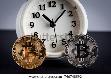 Two bitcoins and vintage alarm clock closeup