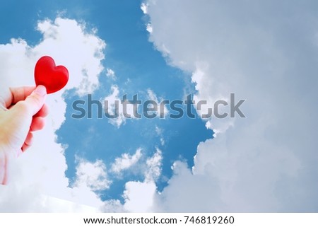 Hand holding red heart on cloud with blue sky background , hand is forwarding  red heart symbol against, concept of  Valentine day or couple of love