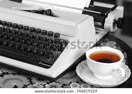 A typewriter and tea. Old things. Black and white photo with colored elements.