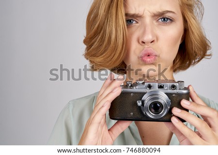 young woman with a camera on a light background portrait                               