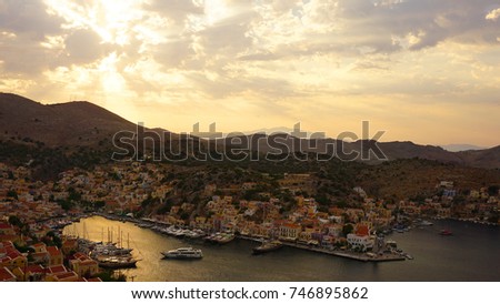 Photo of iconic port of Symi island or Yalos at sunset with beautiful scattered clouds, Symi island, Dodecanese, Greece