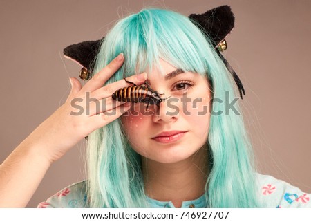 Portrait of a girl in cartoon style with blue hair and cat's ears with madagascar cockroach