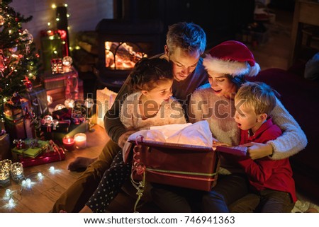 Christmas night. A family opens its gifts, children and parents are very happy to discover a digital tablet in a gift box.