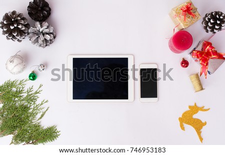 Tablet smartphone cell phone with christmas decoration, silver ribbon, branch of pane, silver snowflake, snow cone, new year