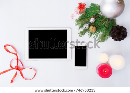 Tablet smartphone cell phone with christmas decoration, silver ribbon, branch of pane, silver snowflake, snow cone, new year