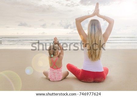 young woman and girl family yoga sunset dawn beach