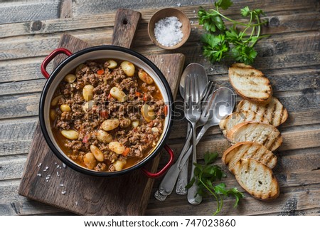 Cannellini beans beef slow-cooker stew on the wooden table, top view. Autumn, winter seasonal, healthy comfort food  Royalty-Free Stock Photo #747023860