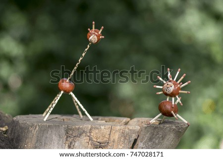 Two funny chestnut animals on tree stump, green background, traditional autumn handcraft, lion and giraffe