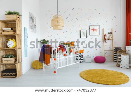 Colorful blanket on white bed in scandinavian style kid's bedroom interior with DIY wooden shelf and yellow accessories